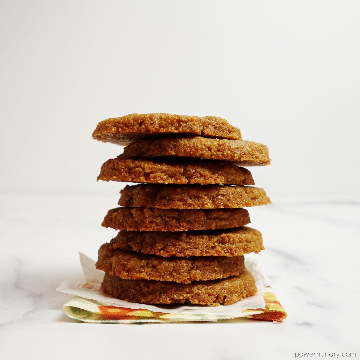 stack of 8 flax shortbread cookies on a floral napkin with a white background