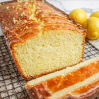 VEGAN GRAIN-FREE LEMON LOAF, partially sliced, on a wire cooling rack