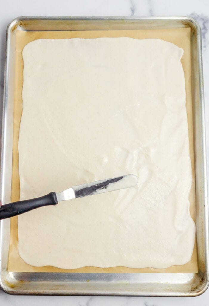 cassava flour batter spread onto a parchment lined baking sheet
