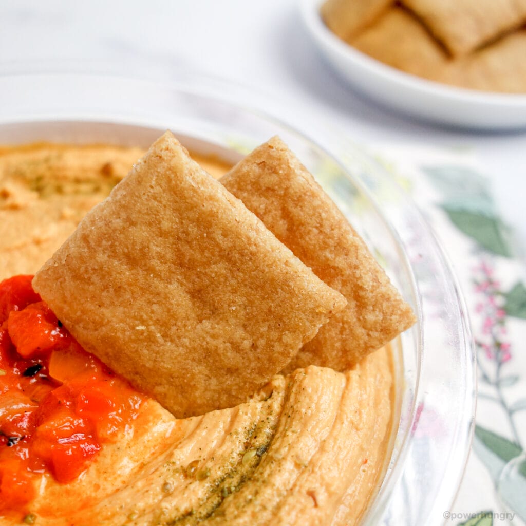 cassava crackers dipped in a bowl of hummus