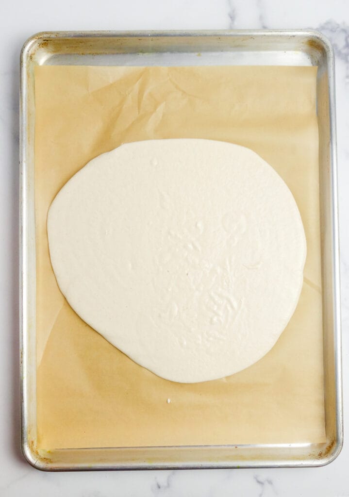 a puddle of cassava flour cracker batter on baking sheet