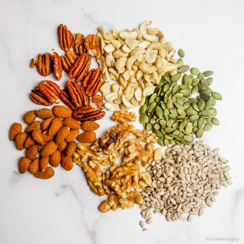 overhead photo of a variety of nuts and seeds on a marble background