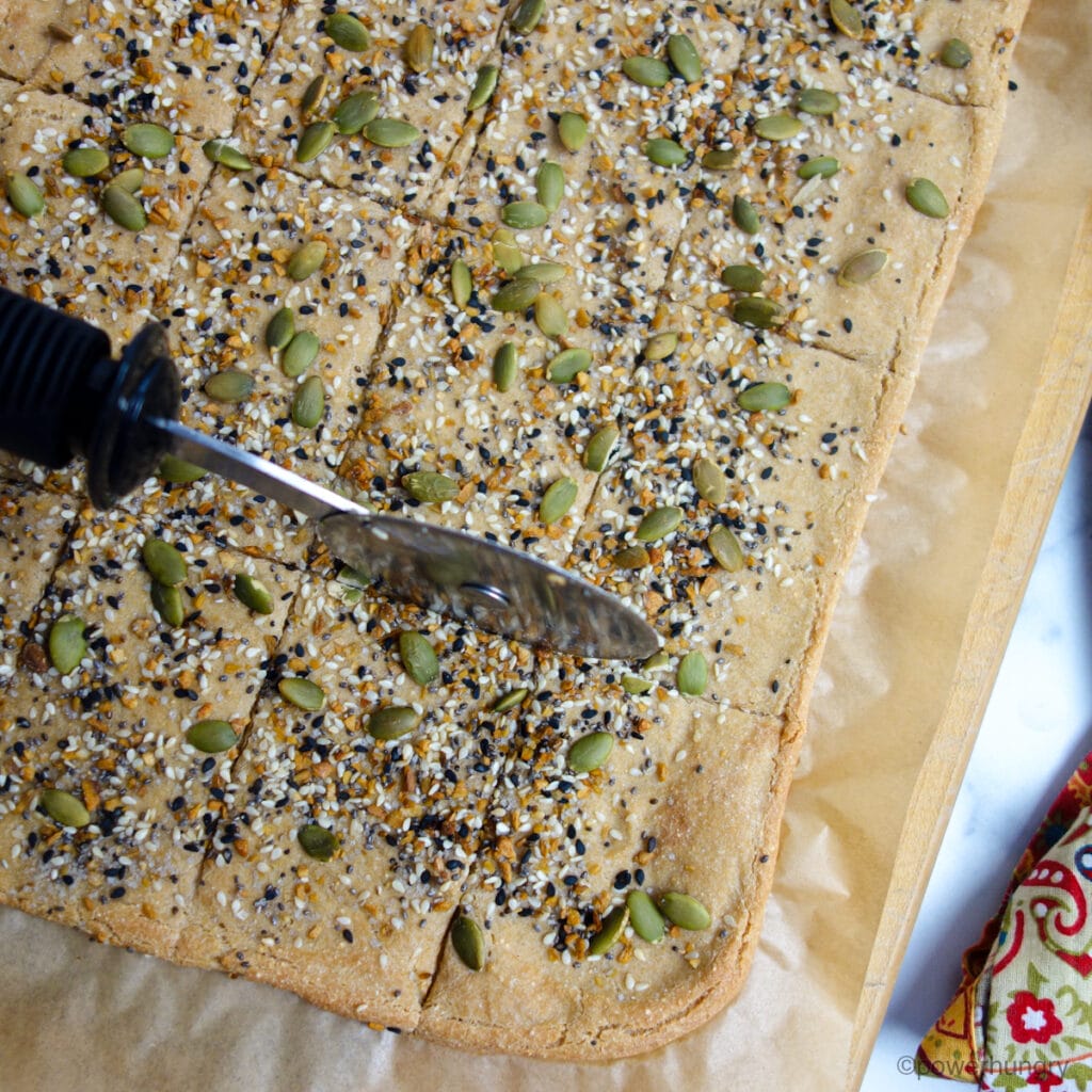 amaranth flatbread being cut into pieces with a pizza cutter