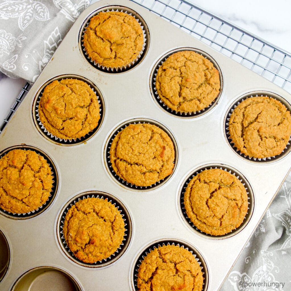 baked vegan applesauce chickpea flour muffins , still in the tin, on a cooling rack