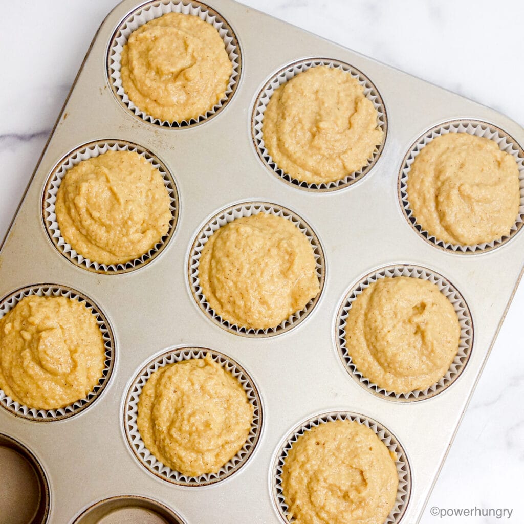 unbaked muffin batter scooped into muffin tin cavities