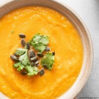 overhead shot of vegan curried pumpkin coconut soup in pottery bowl