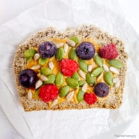 close up of sorghum bread with nut butter seeds and berries on top